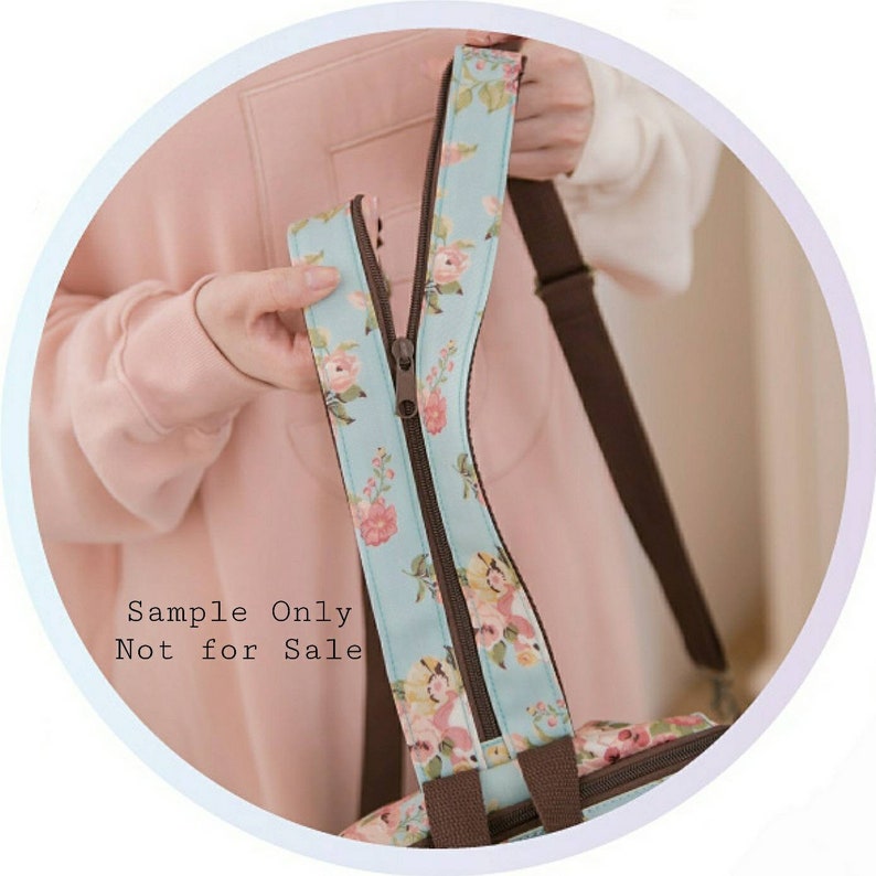 May include: A light blue tote bag with a floral print and brown straps. The bag has a zipper closure and the text "Sample Only Not for Sale" is printed on the front.