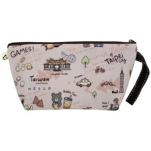 May include: A pink zippered pouch with a brown zipper and a black strap. The pouch has a colourful design featuring illustrations of Taiwanese landmarks, food, and transport. The text "uma hana" and "Taiwan" are printed on the pouch.