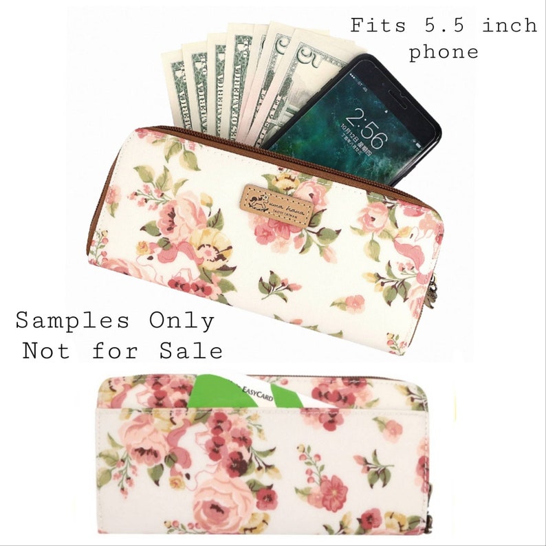 May include: A white zippered wallet with a floral print and a brown leather zipper pull. The wallet has a pocket for a 5.5 inch phone and a card slot. The text "Samples Only Not for Sale" is printed on the image.