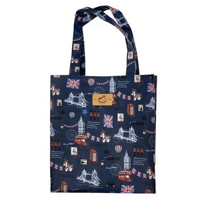 Puede incluir: Una bolsa de tela azul con temática de Londres. La bolsa presenta un patrón repetido de autobuses rojos de dos pisos, el Tower Bridge, el Big Ben y la bandera de la Union Jack. La bolsa tiene una etiqueta de cuero marrón que dice "LONDON".
