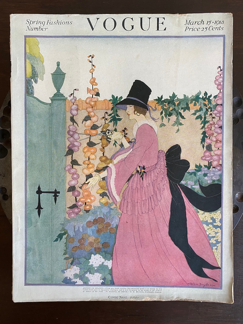 May include: A vintage Vogue magazine cover from March 15, 1918, featuring a woman in a pink dress and black hat standing in a garden. The cover text reads "Spring Fashions Number" and "Price 25 Cents".