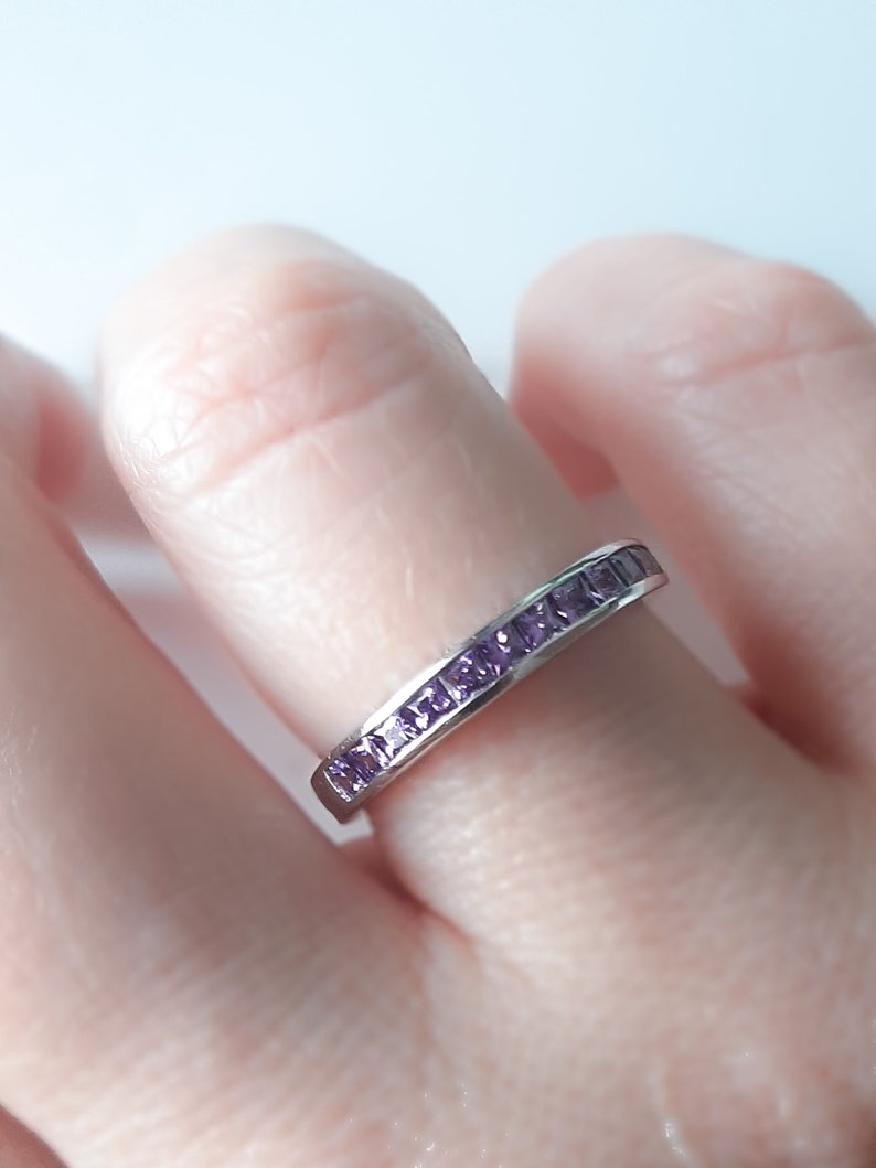 1 carat princess-cut channel set sterling silver ring with brilliant simulated amethyst CZ stones, beautifully packaged in a ribbon-tied gift box. Elegant and versatile band perfect for stacking, wearing alone, or pairing with an engagement ring