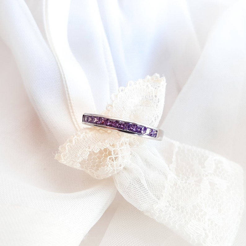 1 carat princess-cut channel set sterling silver ring with brilliant simulated amethyst CZ stones, beautifully packaged in a ribbon-tied gift box. Elegant and versatile band perfect for stacking, wearing alone, or pairing with an engagement ring