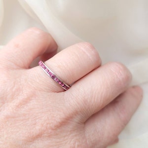 May include: A silver band ring with a row of pink gemstones.