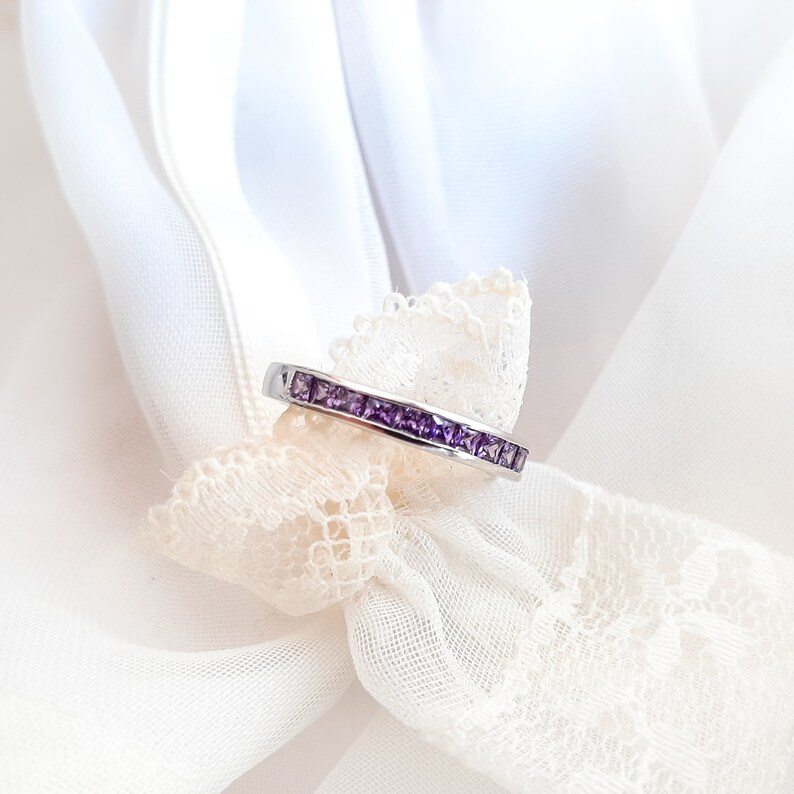 1 carat princess-cut channel set sterling silver ring with brilliant simulated amethyst CZ stones, beautifully packaged in a ribbon-tied gift box. Elegant and versatile band perfect for stacking, wearing alone, or pairing with an engagement ring
