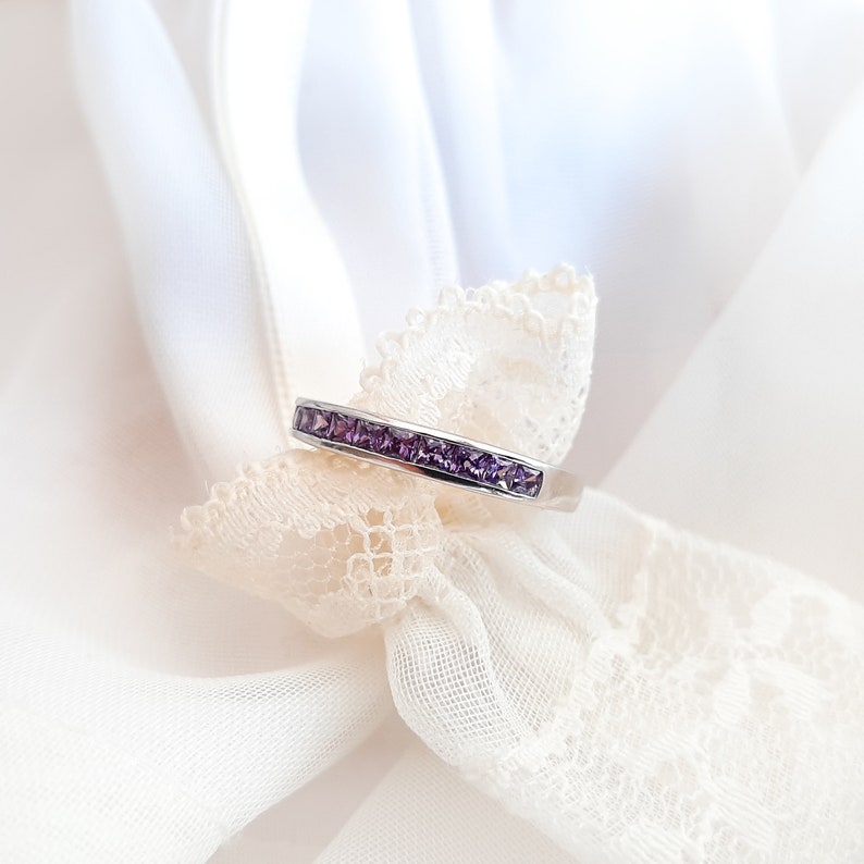 1 carat princess-cut channel set sterling silver ring with brilliant simulated amethyst CZ stones, beautifully packaged in a ribbon-tied gift box. Elegant and versatile band perfect for stacking, wearing alone, or pairing with an engagement ring