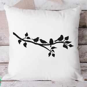 May include: A white throw pillow with a black silhouette of a branch with four birds perched on it. The branch has leaves and the birds are facing different directions.