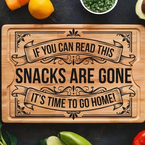 May include: A rectangular bamboo cutting board with a juice groove and black laser-engraved text that reads: IF YOU CAN READ THIS SNACKS ARE GONE IT'S TIME TO GO HOME! The board features decorative scrollwork borders above and below the text.
