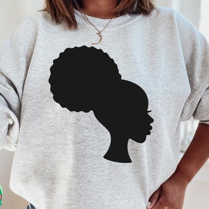 Pu&ograve; includere: Una felpa grigia con una silhouette nera di una donna con un'acconciatura afro.