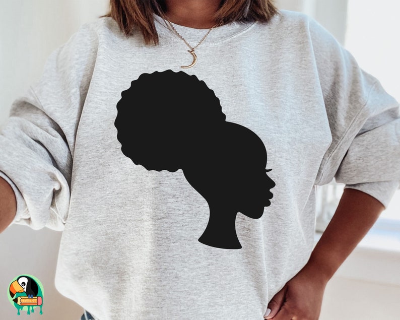 Pu&ograve; includere: Una felpa grigia con una silhouette nera di una donna con un'acconciatura afro.