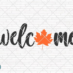 May include: Welcome sign with a black cursive font and an orange maple leaf. The sign is on a white brick background.