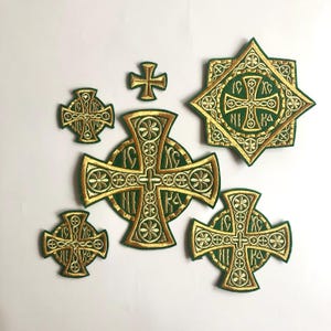 May include: A set of six embroidered patches featuring gold crosses on a green background. The crosses are decorated with intricate details and some have Cyrillic lettering.
