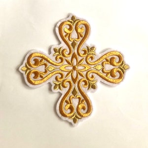 May include: Embroidered gold cross with ornate scrollwork and a central floral design. The cross is outlined in white and features a detailed, symmetrical pattern. This decorative patch is suitable for religious or craft projects.