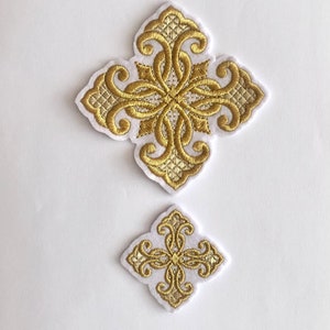 May include: Two gold embroidered cross patches with ornate designs on a white background. The larger cross is approximately 4 inches wide, and the smaller one is about 2 inches wide. The embroidery features intricate patterns.