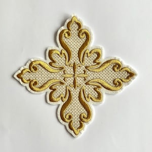 Op de afbeelding: Geborduurde gouden kruisapplicatie met een crèmekleurige rand. Het kruis heeft een sierlijk ontwerp en een getextureerde achtergrond. De applicatie is waarschijnlijk bedoeld voor decoratieve doeleinden, zoals het verfraaien van kleding of accessoires.