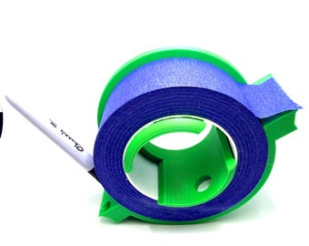 May include: A green and blue tape dispenser with a roll of blue painter's tape. A white pen with the word "Sharpie" is resting on the dispenser. The dispenser is made of plastic and has a circular design.