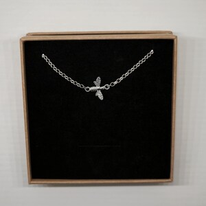 May include: A silver bee charm necklace in a brown box with a black velvet interior.