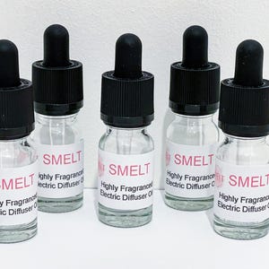 May include: Five clear glass bottles with black dropper tops and white labels. The labels read "SMELT Highly Fragranced Electric Diffuser Oil".
