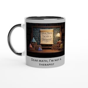 Könnte beinhalten: Weißer Keramikbecher mit schwarzem Innenraum und Henkel. Der Becher zeigt den Text "DEAR MATH, I'M NOT A THERAPIST" und eine Illustration eines Schreibtisches mit mathematikbezogenen Gegenständen.