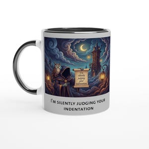 Könnte beinhalten: Weiße Keramiktasse mit schwarzem Henkel und Rand. Die Tasse zeigt eine Fantasy-Illustration einer vermummten Figur, einer Eule und einer Burg unter einem mondbeschienenen Himmel. Auf der Tasse steht "I'm silently judging your indentation."