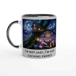 Könnte beinhalten: Weiße Keramik-Tasse mit schwarzem Henkel und Rand. Die Tasse zeigt eine skurrile Illustration einer Baumhausszene unter einem Nachthimmel mit dem Text "I'm not lazy, I'm just caching energy."