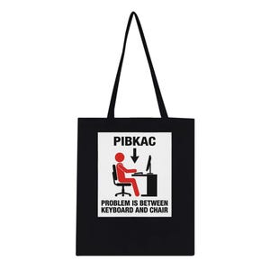 Może przedstawiać: Czarna torba typu tote z białym prostokątem. Zawiera czerwoną postać z patyczaków przy komputerze z tekstem "PIBKAC" powyżej i "PROBLEM IS BETWEEN KEYBOARD AND CHAIR" poniżej. Torba ma czarne uchwyty.