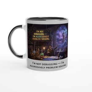 Könnte beinhalten: Weißer Keramikbecher mit schwarzem Innenraum und Griff. Der Becher zeigt eine detaillierte Illustration eines Wissenschaftlerlabors mit dem Text "I'M NOT DEBUGGING - I'M AGGRESSIVELY PROBLEM-SOLVING" auf der Vorderseite.