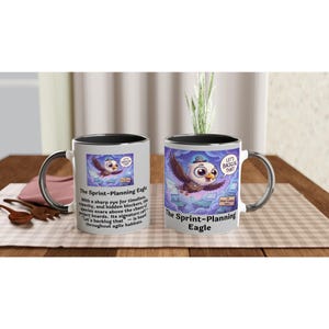 Könnte beinhalten: Zwei weiße Keramikbecher mit schwarzem Innenraum und silbernen Griffen. Jeder Becher zeigt eine Cartoon-Adler-Illustration mit dem Text "The Sprint-Planning Eagle". Auf einem Becher steht der Satz "Let's Backlog That!"