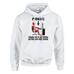 Może przedstawiać: Biała bluza z kapturem z grafiką. Grafika zawiera tekst "PIBKAC" nad ilustracją osoby przy komputerze, z tekstem "PROBLEM IS BETWEEN KEYBOARD AND CHAIR" poniżej. Grafika jest czarno-czerwona.