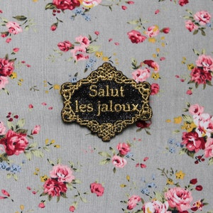 Hello Jealous Brosche &quot;The Precious Distinguished Baroque&quot; Schmuckstück aus schwarzem Paillettenstoff mit gestickter Botschaft aus französischem Goldfaden, hergestellt in Frankreich