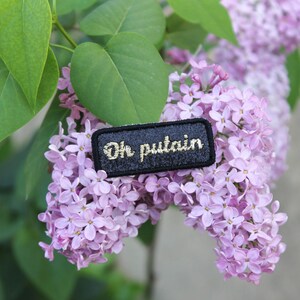 Oh putain brooch (small model) jewel in shimmering sequined fabric, ebony black, embroidered message with gold thread and black outline, made in France