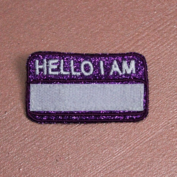 Badge HELLO I AM broche rectangle à bords ronds tissu pailleté violet brodé fil blanc contour fil violet scratch noir fabriquée en France