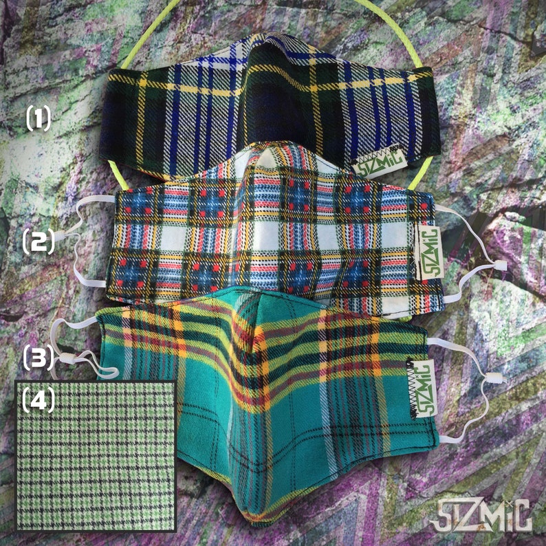 Puede incluir: Tres mascarillas de tela a cuadros con lazos el&aacute;sticos para las orejas. Las mascarillas est&aacute;n superpuestas. La mascarilla superior es negra, verde y blanca. La mascarilla del medio es blanca, roja y verde. La mascarilla inferior es turquesa, amarilla y verde. Cada mascarilla tiene una etiqueta verde con el texto "SZMIC" en ella.