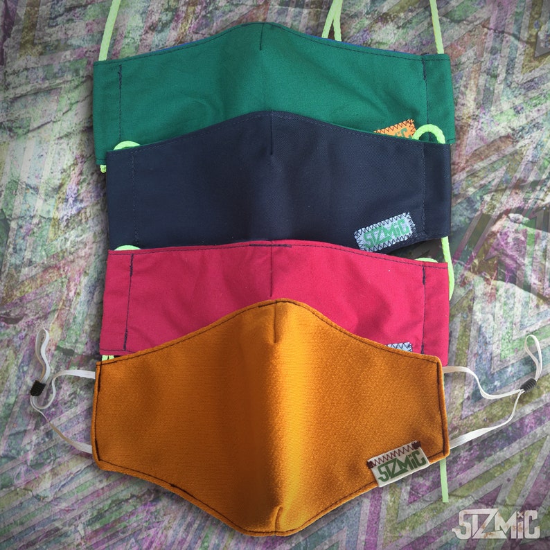 Puede incluir: Cuatro mascarillas de tela en diferentes colores: verde, azul marino, rojo y naranja. Cada mascarilla tiene un peque&ntilde;o logotipo con el texto "SZMIC" en &eacute;l.