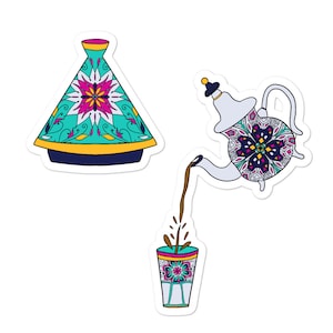 May include: A set of three Moroccan-style ceramic tea serving pieces. A teal and white teapot with a floral design pours tea into a glass with a similar design. A teal and white lidded pot with a floral design sits in the background.