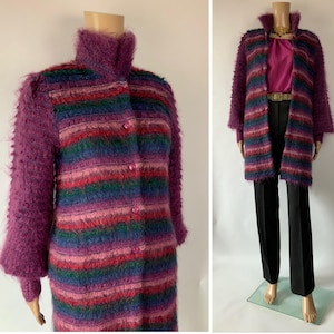May include: A vintage, long-sleeved coat with a high collar and button closure. The coat features a striped pattern in shades of purple, pink, green, and blue. The sleeves and collar are a solid purple, and the coat is displayed on a mannequin.