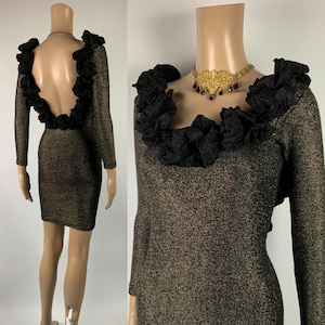 Könnte beinhalten: Ein gold-schwarzes Kleid aus Metallic-Strick mit langen Ärmeln und tiefem Rückenausschnitt. Der Ausschnitt und der Rücken sind mit schwarzem Rüschenstoff verziert. Eine goldfarbene Halskette mit schwarzen Akzenten ist ebenfalls sichtbar.