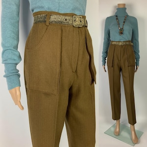 May include: Brown high-waisted pants with large front pockets and a matching gold-tone belt. The pants are paired with a light blue long-sleeve shirt. The belt has a rectangular gold buckle. The pants are displayed on a mannequin.