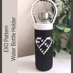May include: Black and white crocheted water bottle holder with a heart design and a handle. The holder is made with a black yarn and white yarn.