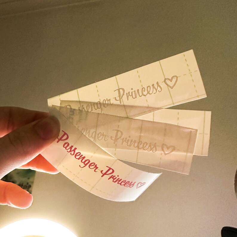 May include: Three white labels with pink text. The top label reads "Passenger Princess" with a pink heart. The middle label reads "Passenger Princess" with a pink heart. The bottom label reads "Passenger Princess" with a pink heart.