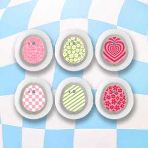 May include: Six different patterned adhesive patches for a medical device. The patches feature designs including smiley faces, flowers, hearts, chequered, stripes, and more.