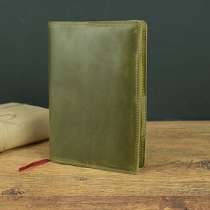 May include: A green leather journal with a red ribbon bookmark. The journal has a stitched edge and a textured surface.
