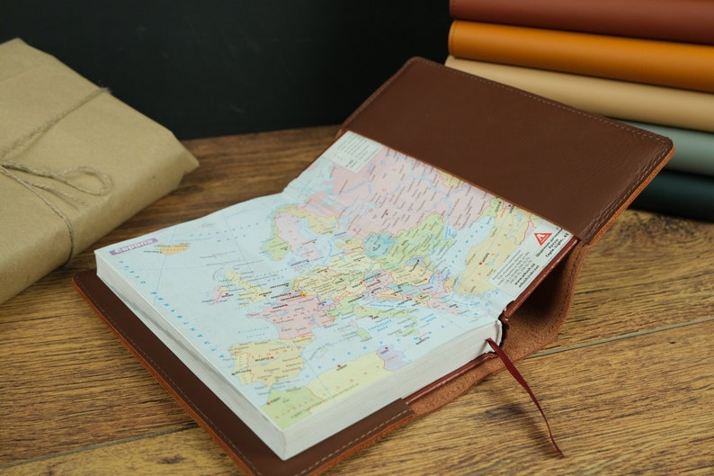 May include: A brown leather-bound journal with a map of Europe inside. The journal is open and the map is visible. The journal has a red ribbon bookmark.