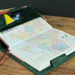 May include: A green leather journal with a map of Ukraine inside. The journal has a red ribbon bookmark and a pocket on the front cover.