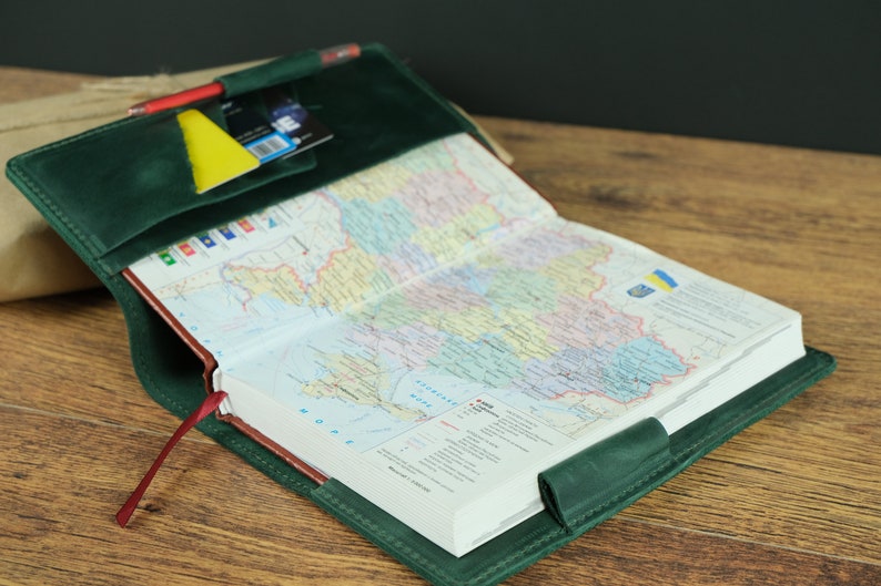 May include: A green leather journal with a map of Ukraine inside. The journal has a red ribbon bookmark and a pocket on the front cover.