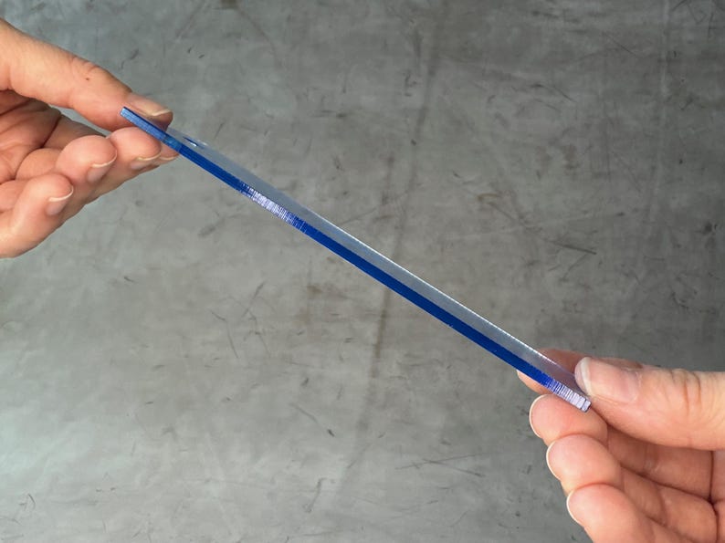May include: A clear plastic ruler with a blue stripe down the center.