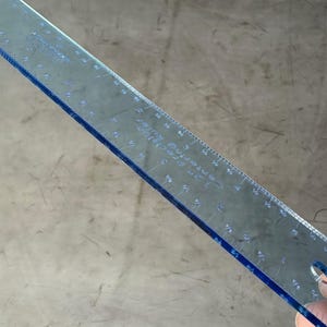 May include: A clear blue plastic ruler with inch markings. The ruler has a hole in the upper right corner.
