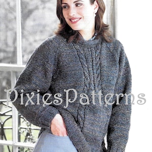 May include: A blue and grey knitted jumper with a cable knit pattern on the front. The jumper has a round neckline and long sleeves.