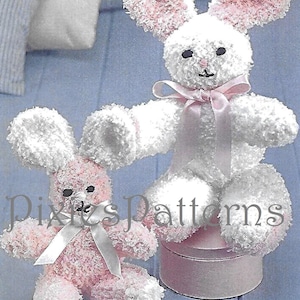 May include: Two sock bunny toys, one white and one pink, with white fluffy fur and pink ears. The bunnies are sitting on a blue surface with a pink gift box.