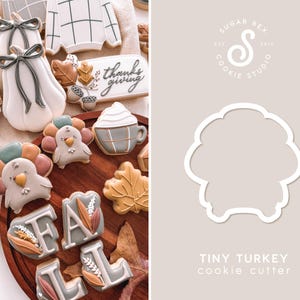 May include: A cookie cutter shaped like a tiny turkey with a rounded body and a small head. The cutter is made of metal and is designed for making cookies. The text "TINY TURKEY cookie cutter" is printed below the cutter.